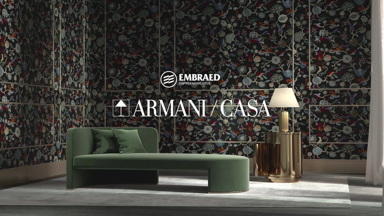 Ambiente Armani/Casa com sofá em veludo verde, luminária dourada e papel de parede bordado, com as assinaturas Embraed e Armani/Casa